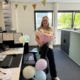 Medewerker met een boeket bloemen bij een versierde werkplek met ballonnen.